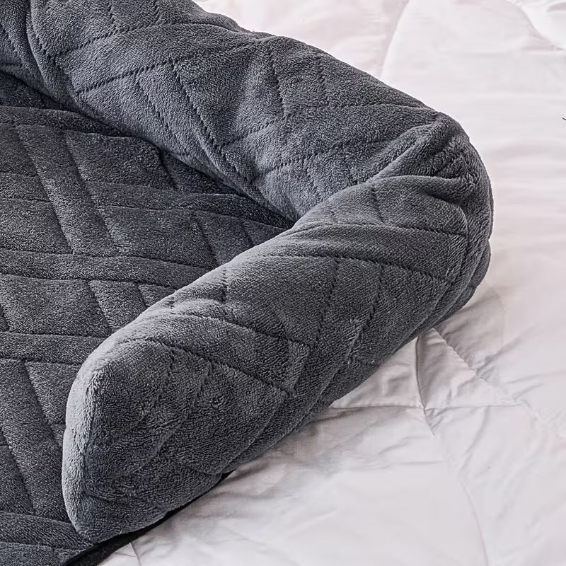 A dark gray quilted U-shaped body pillow pet bed with a plush fleece texture, shown folded over on a white quilted bedspread.