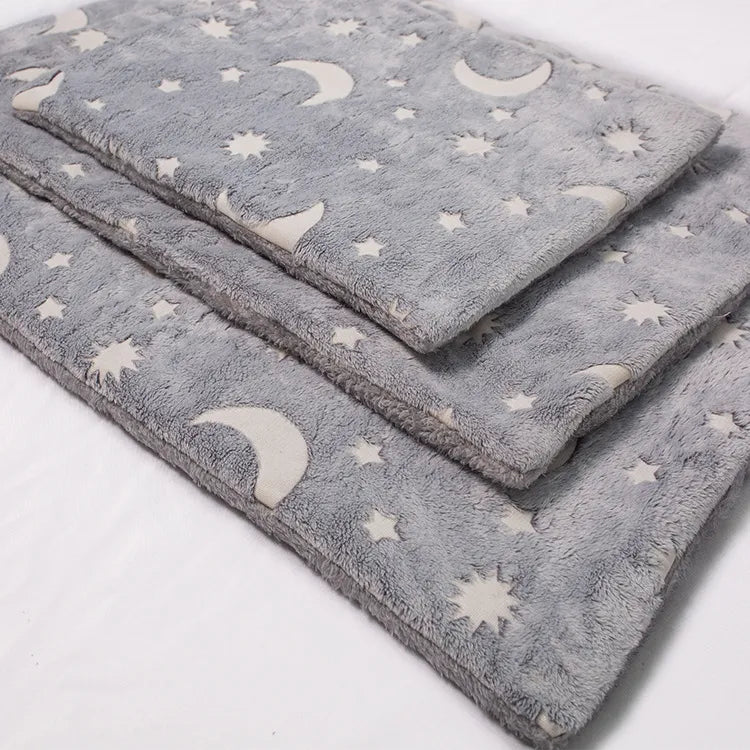 A stack of plush gray blankets with cream-colored crescent moon and star patterns, photographed on a plain white background.