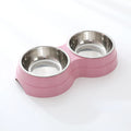 Double stainless steel pet bowl set in a pink plastic base, white background

