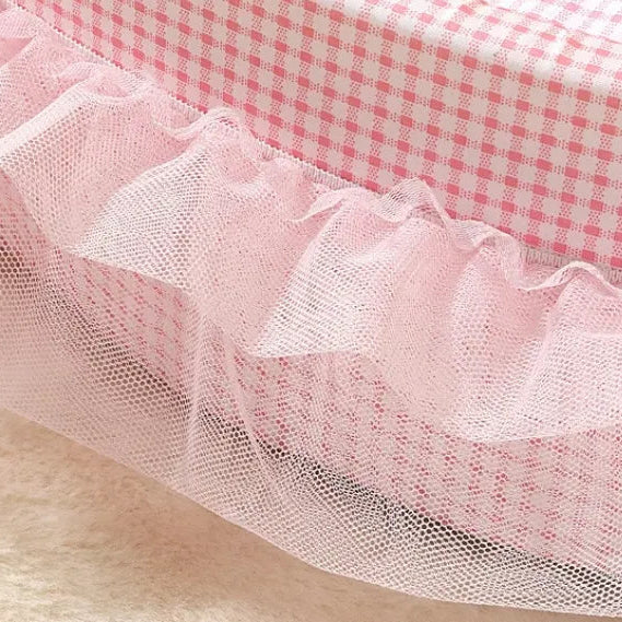 Close-up detail of pink gingham oval pet bed showing layered sheer pink lace ruffle trim and gingham fabric texture