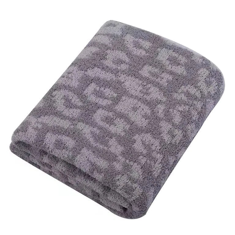 A folded gray plush blanket with a lighter gray leopard or cheetah spot pattern, shown on a solid white background.