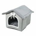 A gray plush pet house with a slanted roof, arched entryway, white faux-fur trim, and a small white bow on the front, shown on a plain white background.