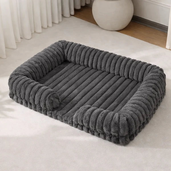 Dark charcoal grey chunky ribbed plush rectangular pet sofa bed with raised bolster sides, shown at a 3/4 angle in a minimalist home setting
