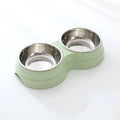 Double stainless steel pet bowl set in a green plastic base, white background
