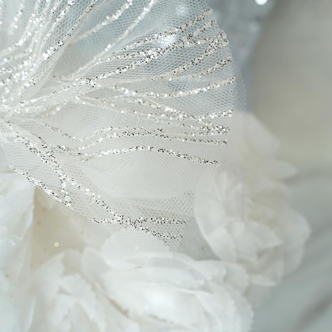 Close-up of white tulle with silver glitter swirls and layered white fabric flowers on a pet dress