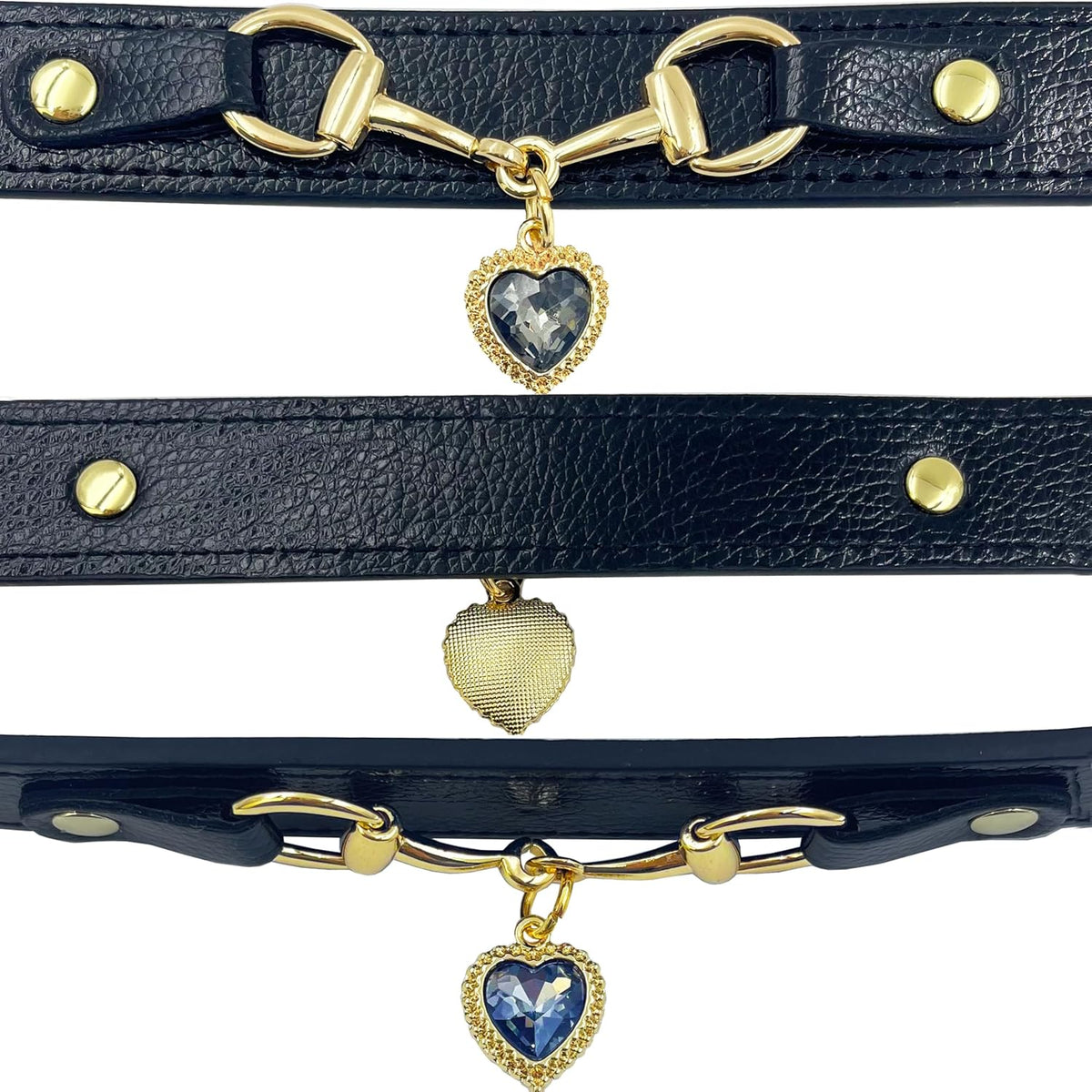 Three black leather pet collars with gold snaffle-bit hardware and dark blue crystal heart charm pendants, shown in a close-up detail flat lay on a white background