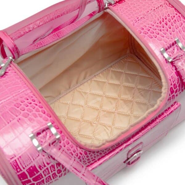 A close-up of a bright pink crocodile-embossed leather bag shown open, revealing a quilted beige interior lining and silver-tone hardware.
