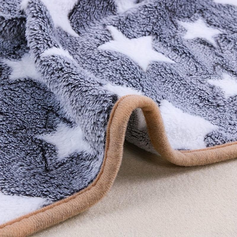 Close-up of a plush fleece blanket with a gray and white star pattern and a tan border, draped to show texture and edge.