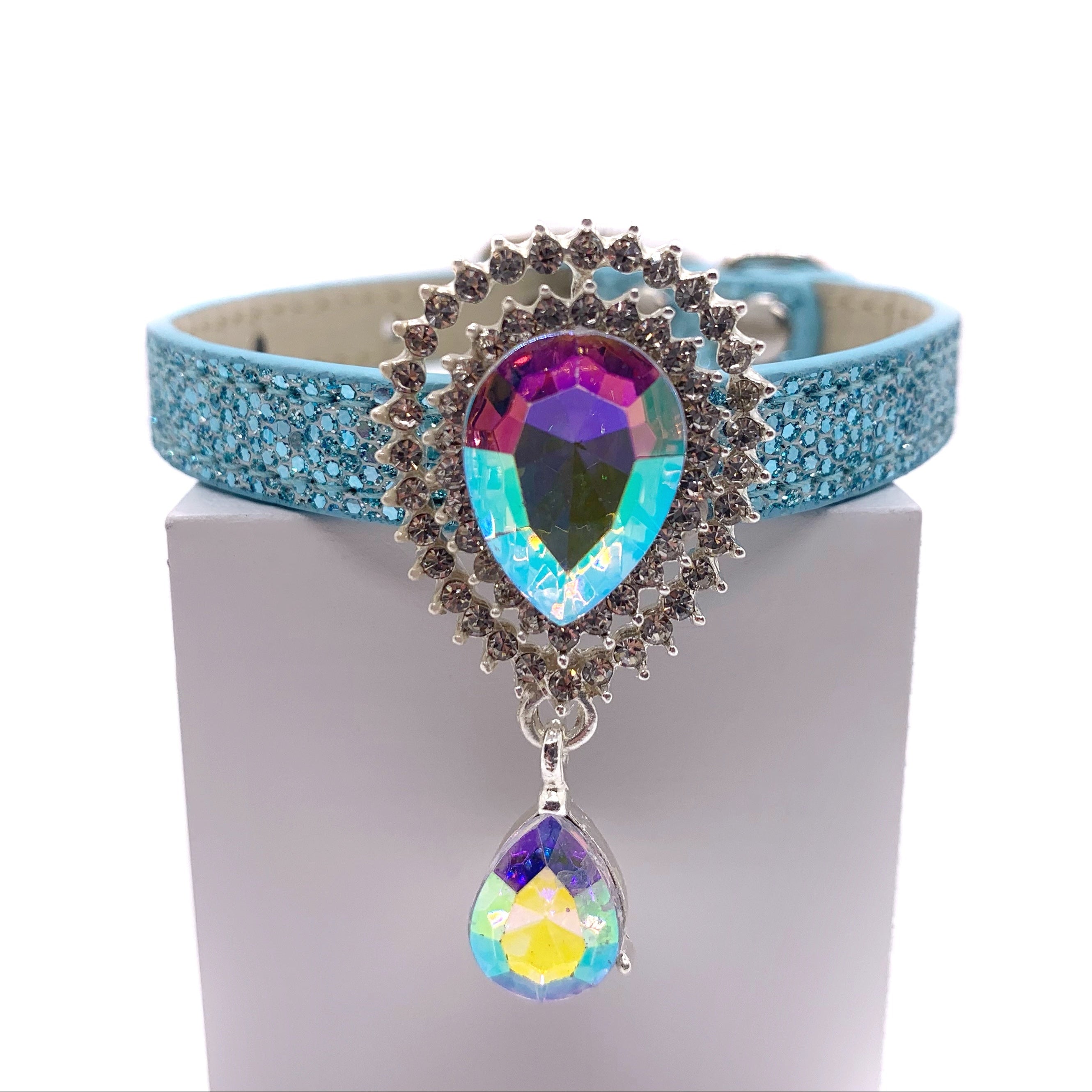 Light blue glitter dog collar with large aurora borealis teardrop crystal sunburst centerpiece and dangling AB crystal drop on white stand