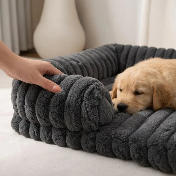 Golden Retriever puppy sleeping inside a dark charcoal grey chunky ribbed plush pet bed, with a hand touching the soft fabric, in a cozy home setting