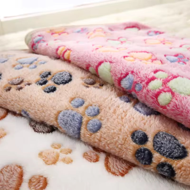 Stack of soft blankets with paw print patterns on a light background