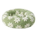 Sage green plush round donut pet bed with an all-over white daisy floral pattern, shown at a 3/4 angle on a white background