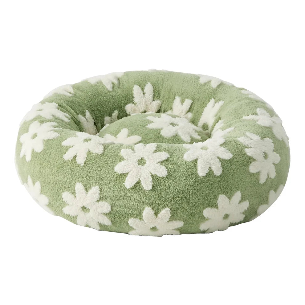 Sage green plush round donut pet bed with an all-over white daisy floral pattern, shown at a 3/4 angle on a white background
