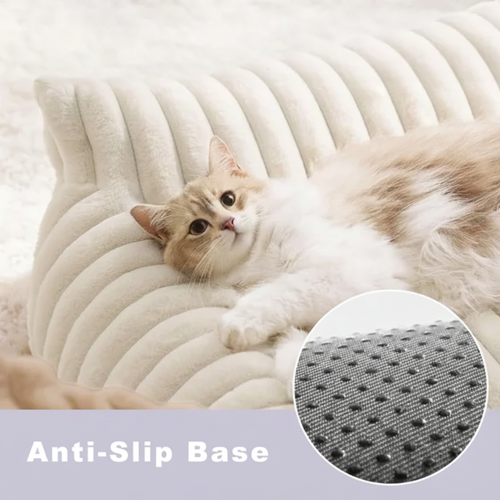 Orange and white tabby cat lounging on a cream ribbed channel-tufted plush pet sofa bed, with a close-up inset of the textured grey anti-slip base and text reading Anti-Slip Base