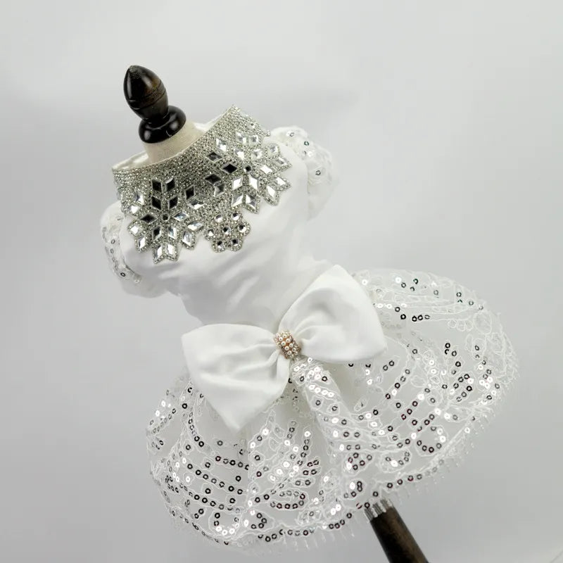 White dog wedding dress with a silver rhinestone collar, sequined lace skirt, and satin bow with a jeweled center, displayed on a mannequin