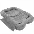 Oversized grey plush human-sized dog bed with bone-shaped bolster sides and matching faux fur blanket on white background