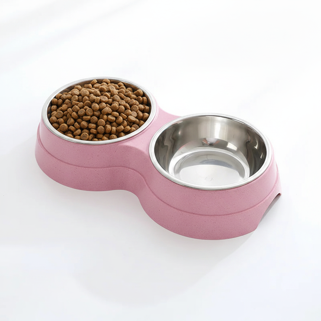 Double stainless steel pet bowl set in a pink plastic base, one bowl filled with dry kibble and one empty, white background
