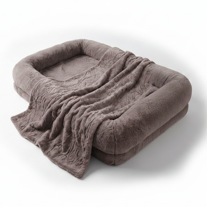 Oversized dusty mauve plush human-sized dog bed with bolster sides and matching faux fur blanket on white background