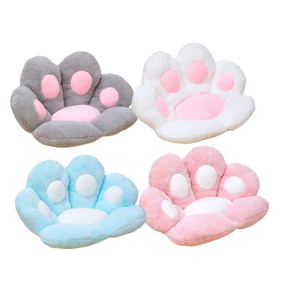 Four-color variant flat lay of plush paw-shaped pet bed cushions on a white background: grey with pink toe pads (top left), white with pink toe pads (top right), powder blue with white toe pads (bottom left), and blush pink with white toe pads (bottom right)