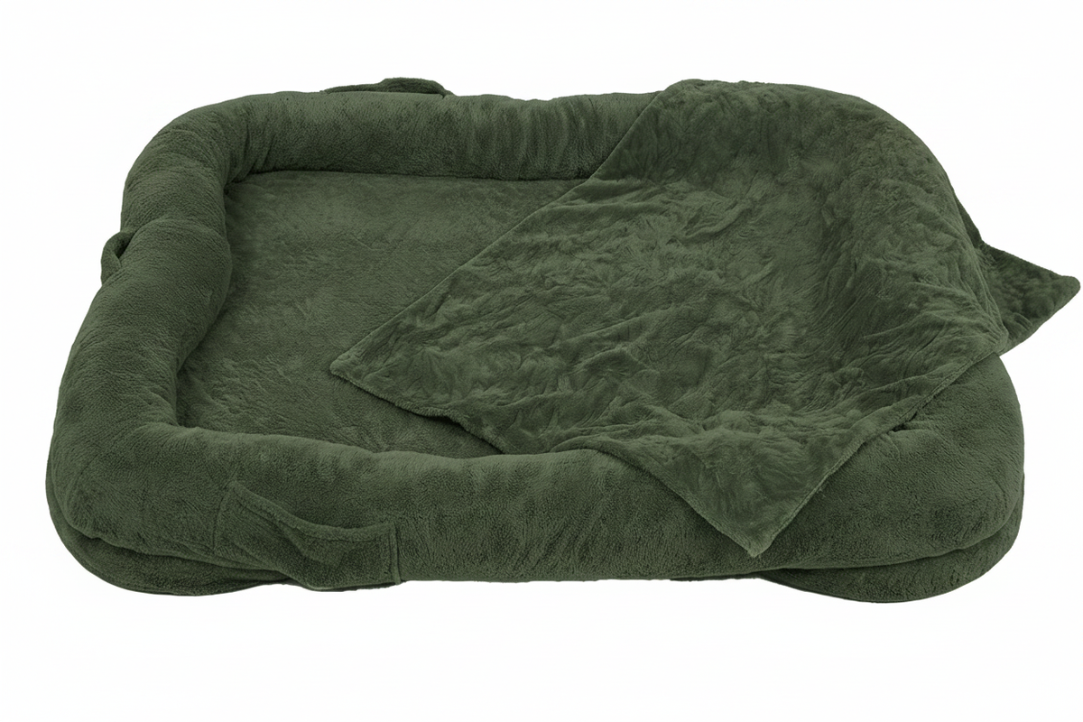 Oversized olive green plush human-sized dog bed with bone-shaped bolster sides and matching faux fur blanket on white background
