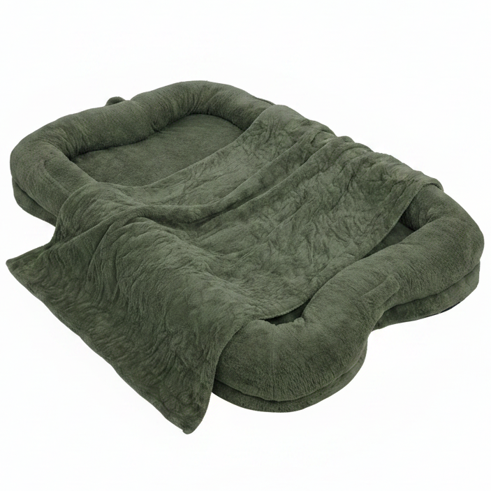 Oversized olive green plush human-sized dog bed with bone-shaped bolster sides and matching faux fur blanket on white background