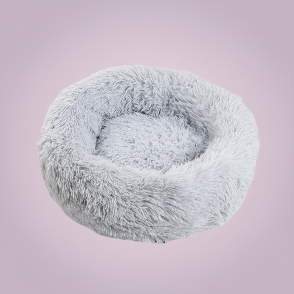Light grey round donut pet bed with long shaggy faux fur and a deep cushioned center, shown against a soft mauve-lavender background