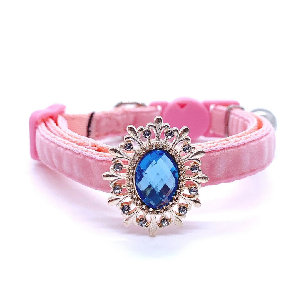 Pink pet collar with a decorative gold and blue gemstone on a white background for cats and dogs