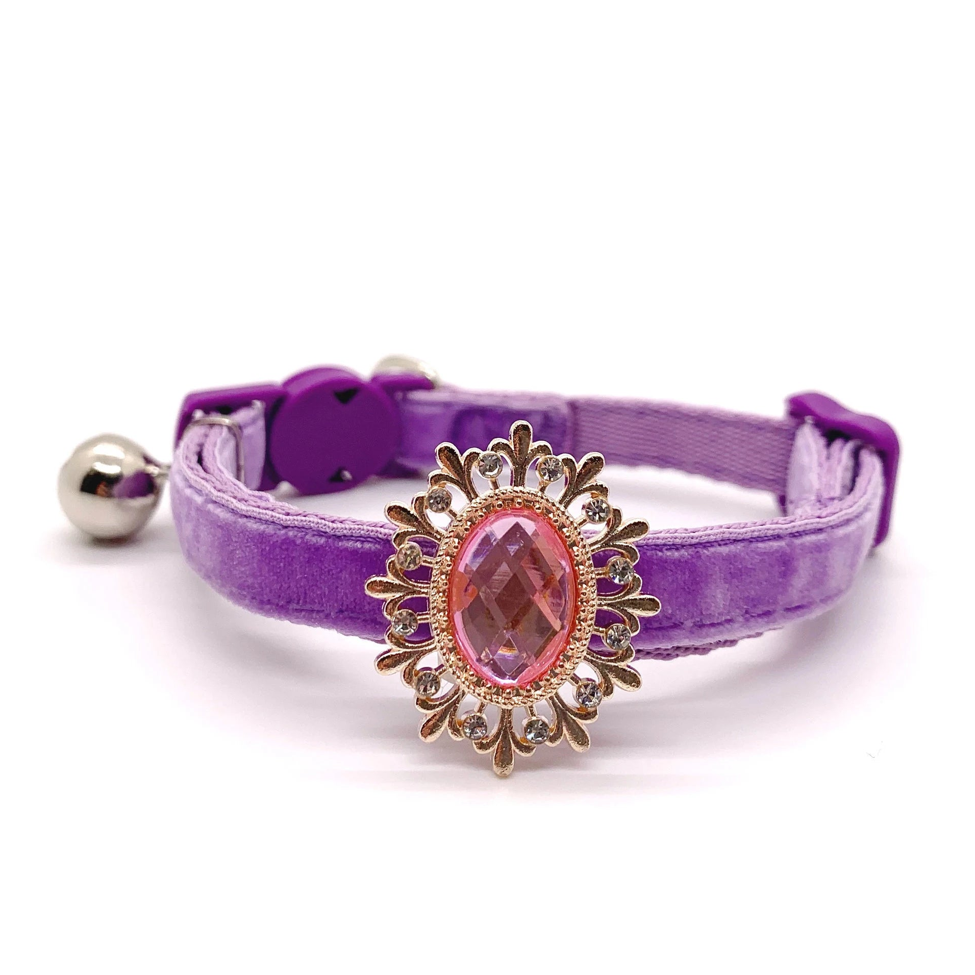 Purple velvet pet collar with a decorative gold and pink gemstone for cats and dogs on a white background