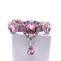 Pink glitter pet collar with three rose pink heart crystal charms in rhinestone halo settings, center charm with dangling pink teardrop crystal drop, laid flat showing full length with rhinestone-encrusted buckle for cats and dogs