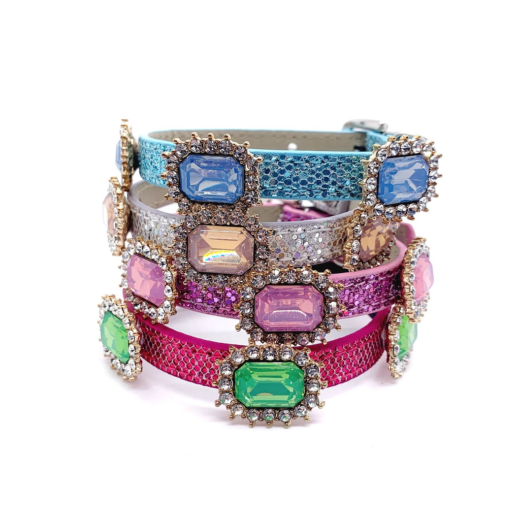 Stacked luxury pet collars with emerald-cut crystal charms in blue, iridescent, pink, and green on teal, silver, lavender, and hot pink snakeskin bands