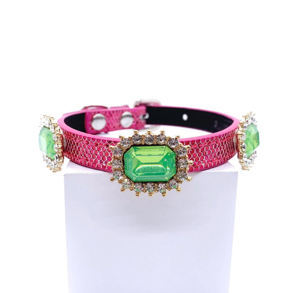 Hot pink metallic honeycomb texture pet collar with three peridot green emerald-cut crystal charms in gold rhinestone sunburst halo settings displayed on stand for cats and dogs