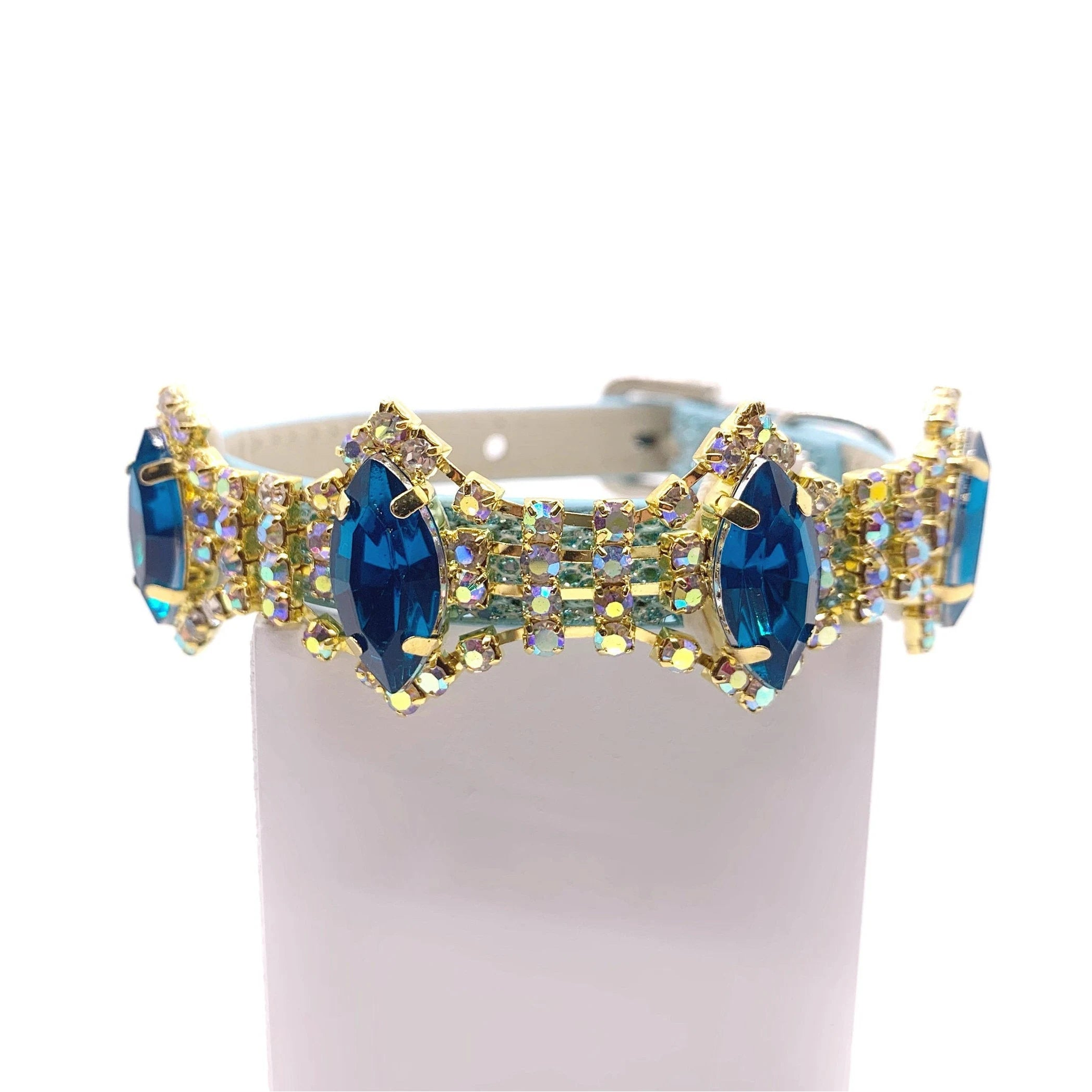 Blue iridescent glitter pet collar with full-band sapphire blue marquise crystals and aurora borealis AB rhinestone accents in gold settings displayed on stand for cats and dogs