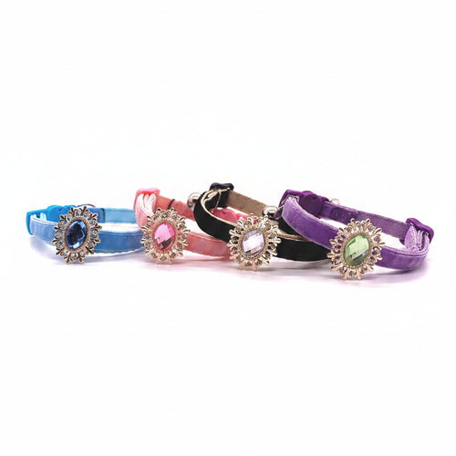 Luxury petcollar collection featuring baby blue with sapphire oval crystal sunflower brooch, pink with rose pink oval crystal sunflower brooch, black with clear crystal sunflower brooch, and purple with peridot green oval crystal sunflower brooch, all with rhinestone accent petals and silver bells