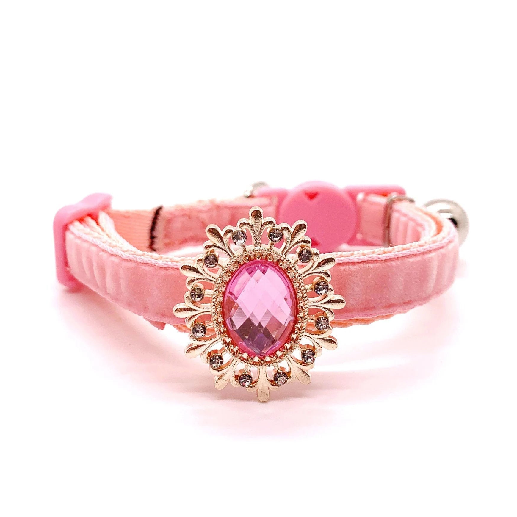 Pink pet collar with a decorative gold and pink gemstone on a white background for cats and dogs