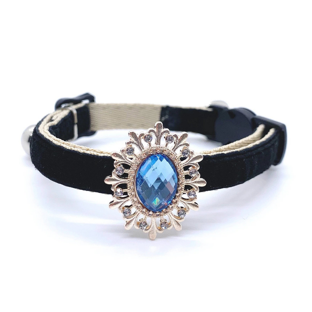 Black pet collar with a decorative gold and blue gemstone on a white background for cats and dogs