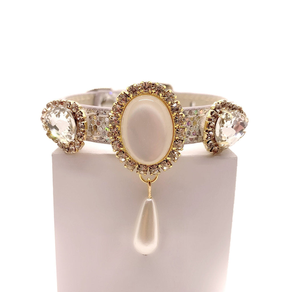 Luxury white leather pet collar with rhinestone-encrusted oval centerpiece, crystal side gems, gold accents, and a dangling pearl drop charm