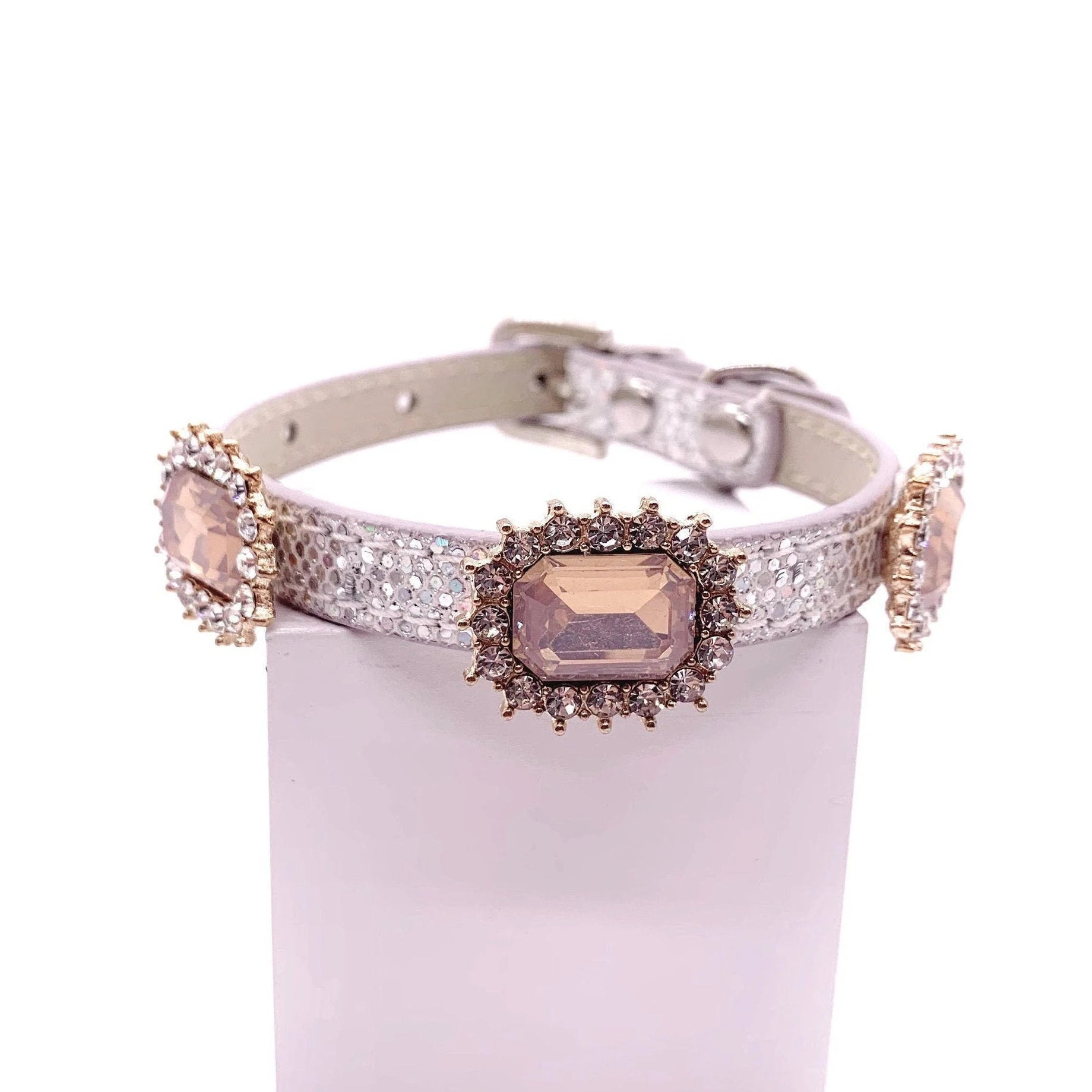Silver iridescent glitter pet collar with three champagne emerald-cut crystal cabochon charms in gold rhinestone halo settings displayed on stand for cats and dogs