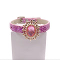 Pink glitter pet collar with gold ornate sunburst brooch and rose pink faceted oval crystal centerpiece with rhinestone accents displayed on stand for cats and dogs