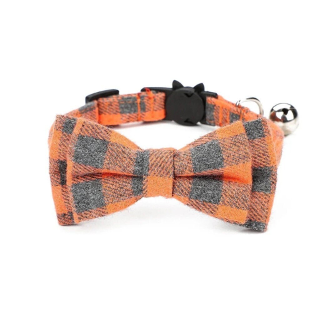 Orange and gray plaid bow tie dog collar with a bell on a white background