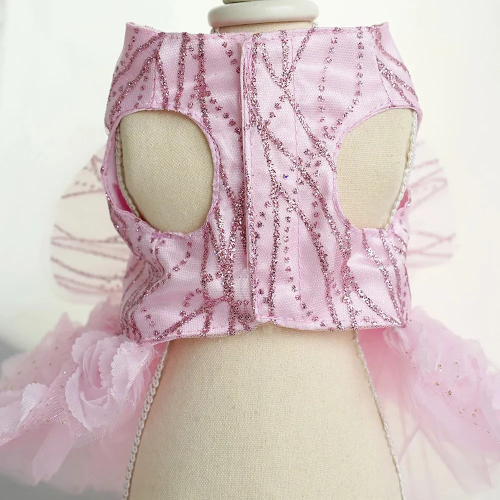 Underside view of a pink dog dress with glitter swirl patterns, two leg openings, a center closure, and a ruffled tulle skirt