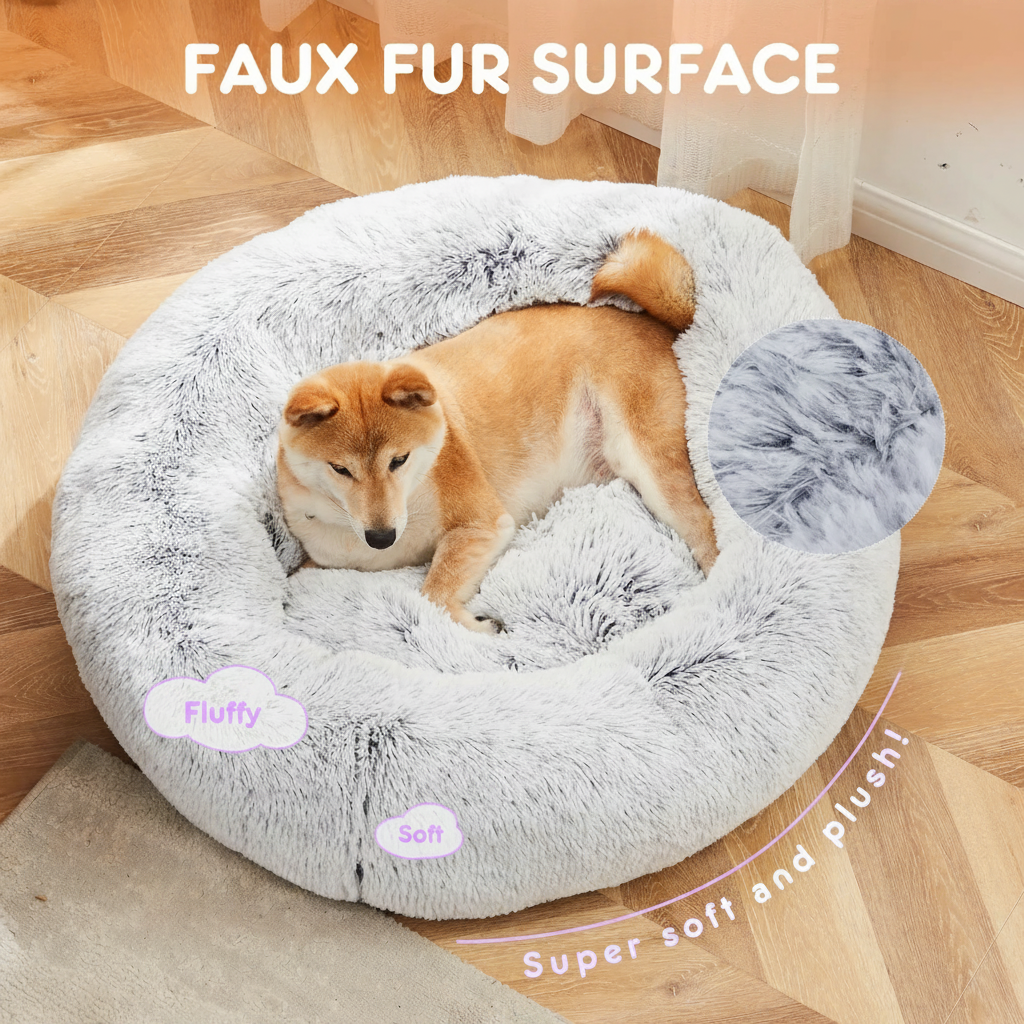 Shiba Inu lying in a large light grey long shaggy faux fur round donut pet bed on a herringbone wood floor, with a close-up fabric swatch inset and text callouts reading Faux Fur Surface, Fluffy, Soft, and Super soft and plush