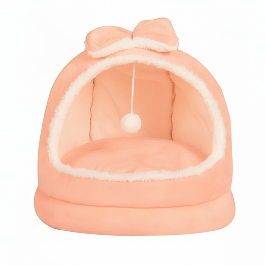 Blush pink plush dome cat bed with matching pink bow on top, hanging white pom pom ball, cream interior lining, on a clean white background