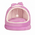 Purple plush dome cat bed with matching purple bow on top, hanging white pom pom ball, cream interior lining, on a clean white background