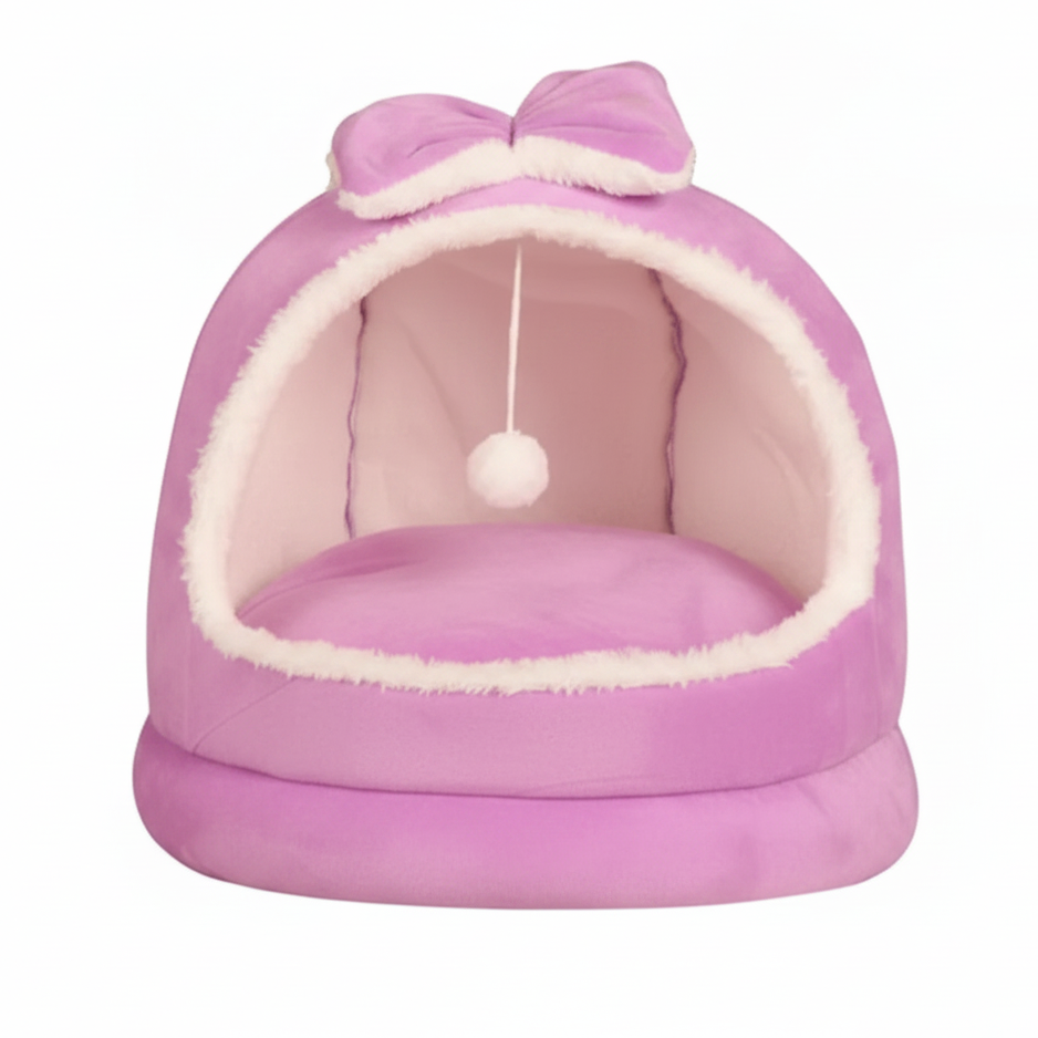 Purple plush dome cat bed with matching purple bow on top, hanging white pom pom ball, cream interior lining, on a clean white background