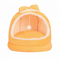 Yellow plush dome cat bed with matching orange bow on top, hanging white pom pom ball, cream fluffy interior lining, on a clean white background