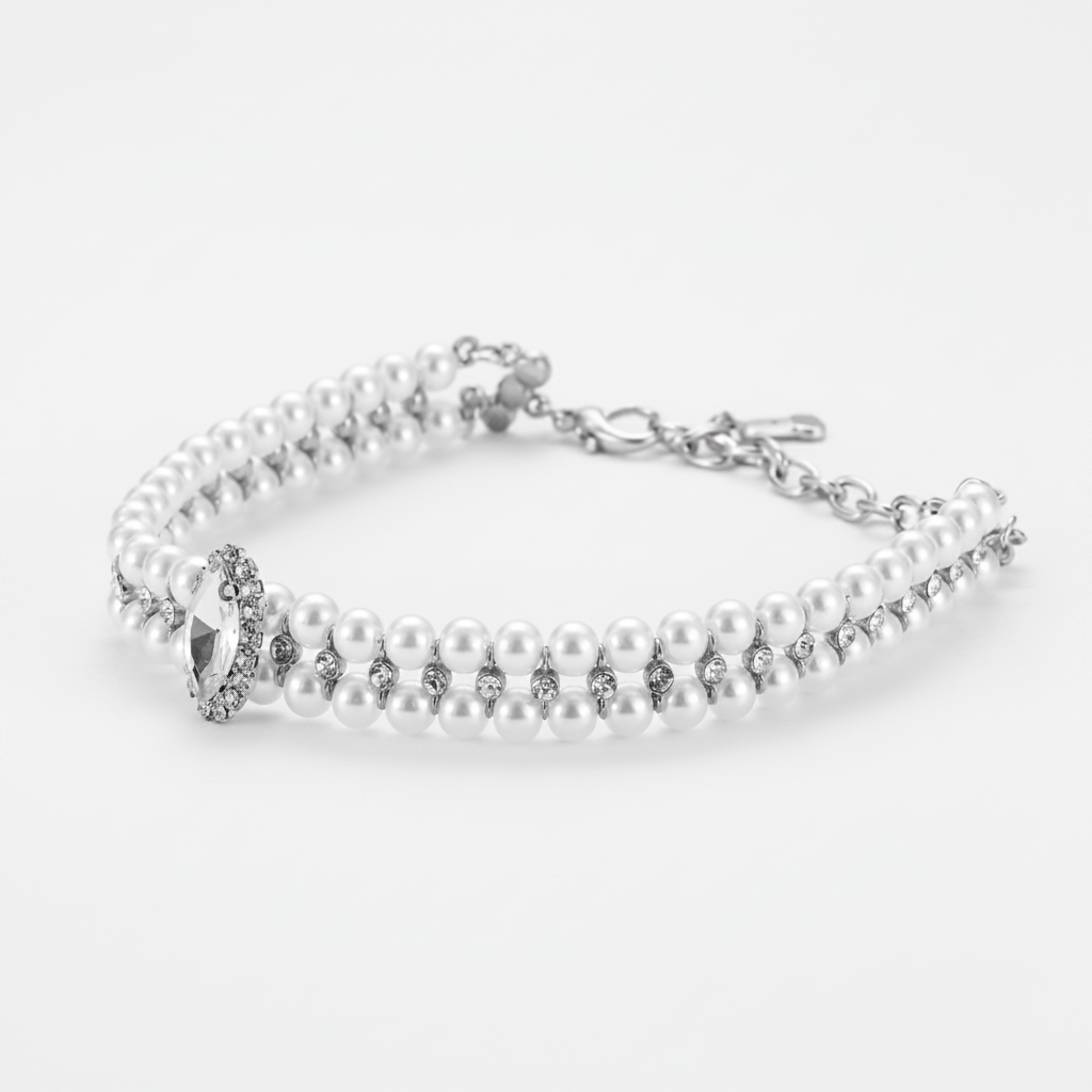 Double-strand white pearl pet collar with silver hardware, small crystal accents between the pearls, and a marquise-cut clear crystal centerpiece surrounded by a halo of small crystals, shown in a 3/4 angle view on a light grey background