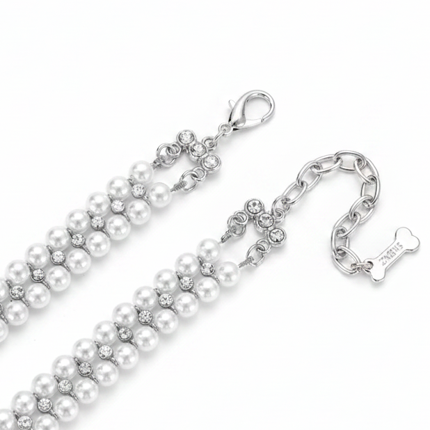 Close-up detail shot of the double-strand white pearl pet collar showing the silver lobster clasp closure, crystal flower connector hardware, crystal accents between the pearls, adjustable chain extension, and a small silver bone charm tag, on a white background