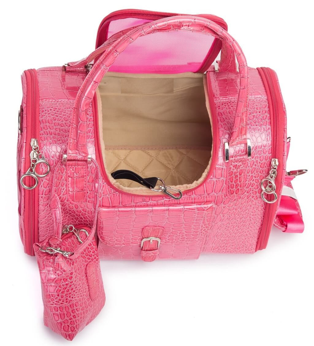 A bright pink crocodile-embossed pet carrier with an open top, dual top handles, a detachable shoulder strap, a matching zippered pouch, and a beige interior lining, shown on a white background.