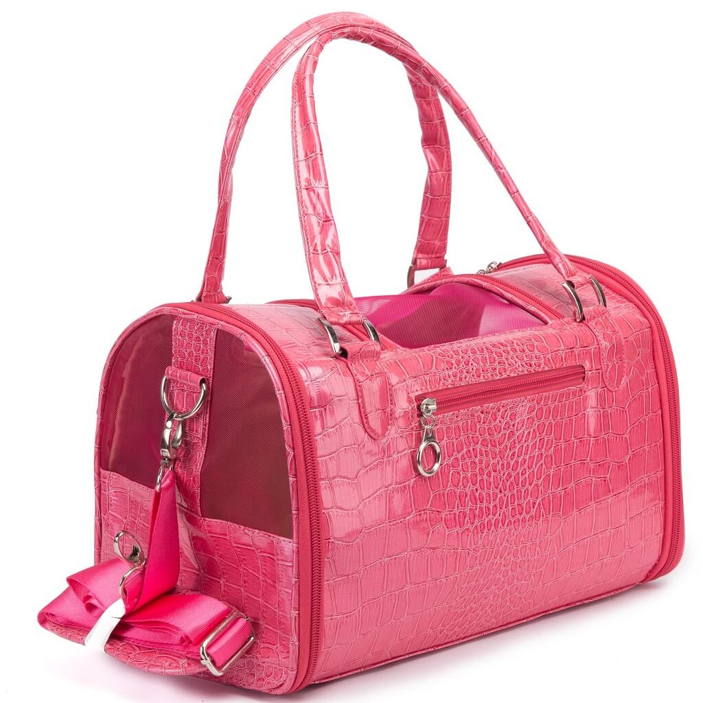 A bright pink pet carrier bag with an embossed crocodile pattern, featuring dual top handles, a zippered main compartment, and a detachable shoulder strap with a bow, shown on a white background.