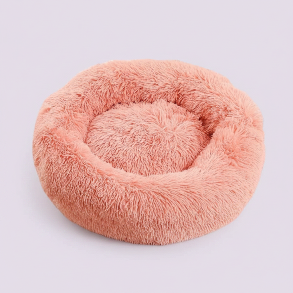 Peach pink round donut pet bed with long shaggy faux fur and a plush cushioned center, shown against a soft lavender background